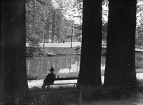 808106 Afbeelding van een man op een bankje in het singelplantsoen langs de Stadsbuitengracht te Utrecht, met op de ...